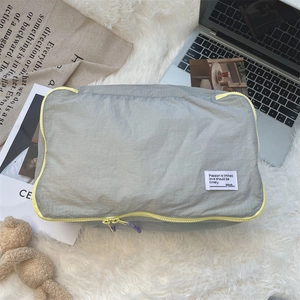 Close-up of lightweight grey travel organizer with bright yellow zipper and ripstop texture