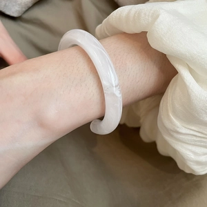 Close-up of a white resin bangle with marble texture worn on a woman's wrist