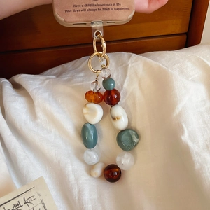 Detail of vintage acrylic marbled beads and gold clasp on a stylish phone charm strap