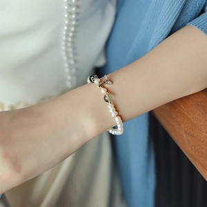 Detail of freshwater pearl bracelet with green faceted beads and a gold fish tail charm