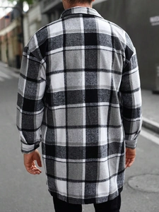 Rear view of a man wearing a long black and white plaid flannel shirt jacket on a city street