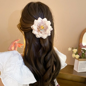 Pink fabric rose hair clip with 3D petals shown on long wavy hair for elegant styling