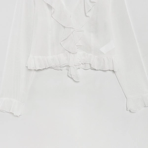 Detail of white chiffon blouse showing ruffle trim and front tie fastening closure