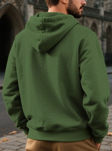 Detail of olive green textured jacquard knit fabric on a men's long sleeve hoodie