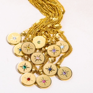 Macro detail of 18K gold plated stainless steel starburst pendants with colorful birthstones