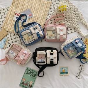 Detail of canvas crossbody bag with clear window pocket and cute astronaut badges