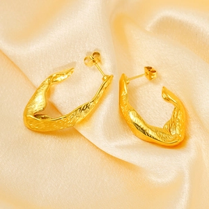 Détail de boucles d'oreilles C irrégulières plaquées or 18K avec texture brossée sur soie
