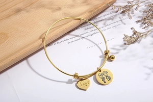 Detailaufnahme des verstellbaren goldfarbenen Armbands mit Love-Herz und Motiv-Anhängern