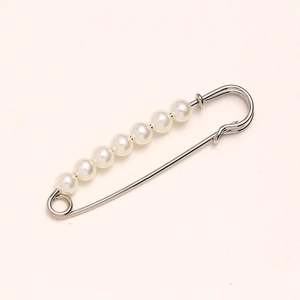 Detail shot of silver safety pin waist cincher with white pearls on pink background