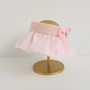 Close-up of pink sun visor with bow, mesh brim and cute orange charm on a display stand