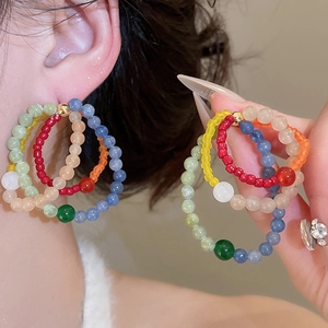 Detail of colorful bohemian layered seed bead hoop earrings with vibrant resin stones