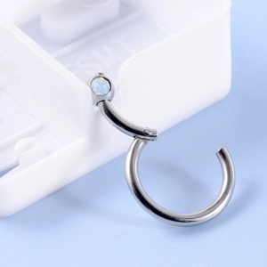 Detail of silver hinged nose ring with teardrop opal stone on a display stand