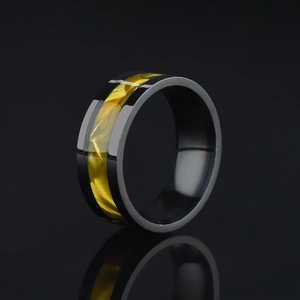 Detail of a polished black stainless steel ring with a textured yellow resin inlay