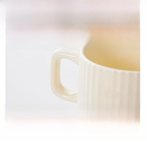 Close-up of cream ceramic mug featuring vertical relief texture and ergonomic square handle