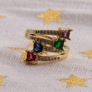 Macro d'une bague en cuivre plaqué or avec quatre pierres de zircon carrées colorées