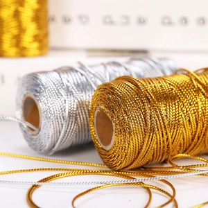 Vista dettagliata dei cordoncini intrecciati metallici oro e argento per confezioni