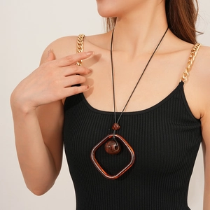 Macro view of a long vintage necklace with amber square resin pendant on a black cord