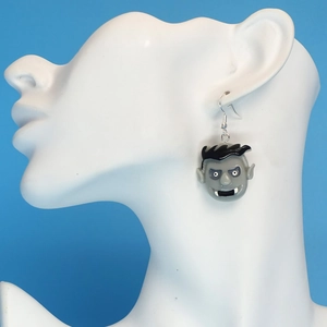Macro side view of novelty Halloween zombie earrings on a white mannequin model