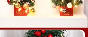 Close-up of mini lit Christmas tree with red gold ornaments and LED lights on tabletop