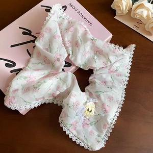 Détail d'un chouchou floral avec bordure en dentelle et fleur jaune sur un livre rose