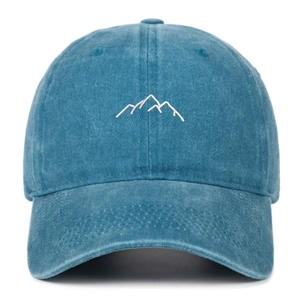 Detailed close-up of white mountain embroidery on washed blue cotton baseball cap