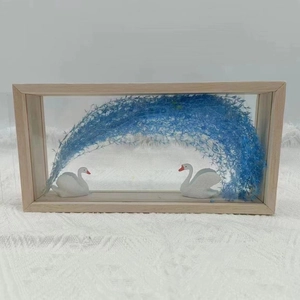 Detail view of wooden acrylic display box with white swans and blue dried floral arch