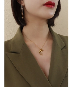 Close-up of golden dolphin pendant necklace and geometric earrings on a model