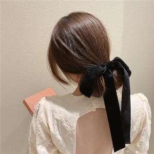 Detailed back view of a large black velvet bow hair clip on brown hair with high texture