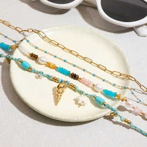Gros plan de bracelets bohèmes avec pierres naturelles, perles et coquillages sur plateau