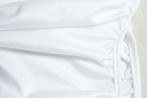 Close-up of white dress showing textured fabric, ruching details and drawstring design