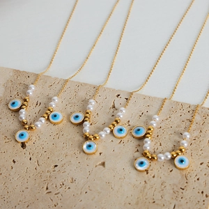 Vintage evil eye pearl necklaces in gold plating displayed on a natural stone base