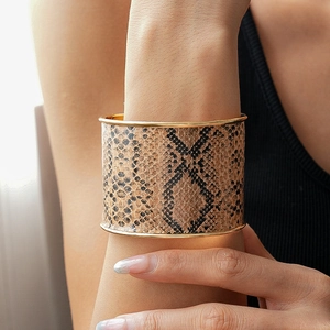 Detail of wide cuff bracelet featuring realistic python texture with gold metallic edges