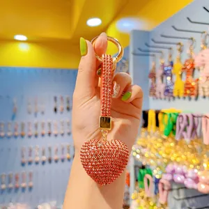 Macro shot of a red rhinestone heart keychain with a gold ring and leather strap