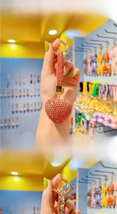 Macro shot of a red rhinestone heart keychain with a gold ring and leather strap