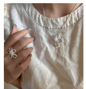 Detail of silver floral necklace and ring set with sparkling zircon on a female model