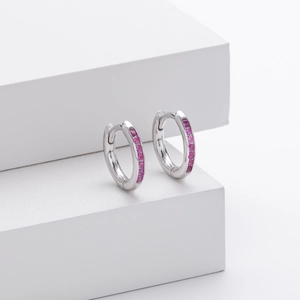 Macro shot of silver S925 earrings with pink zircon stones on a white geometric platform