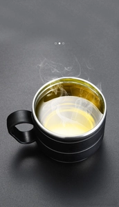 Detailed macro view of a matte black double-walled stainless steel tea cup with rising steam