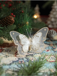 Gros plan d'un papillon décoratif crème avec paillettes dorées et détails en plumes