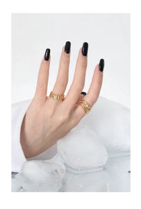 Detailed view of gold lava texture ring and layered zirconia band worn on finger