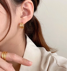 Detail of woven golden knot earrings and matching ring on model for a minimalist look