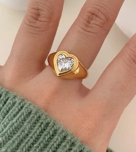 Macro view of wide gold band ring featuring a large heart-cut clear zircon stone inlay