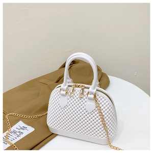 Detail of white PVC jelly bag with woven texture, gold zipper, and chain strap on a table