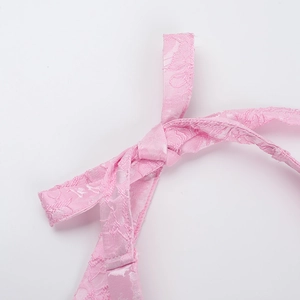 Detailed close-up of the delicate pink lace texture and elegant bow detail on the dress