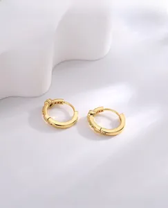 Detail of gold hoop earrings with sparkling zircon inlay on white background