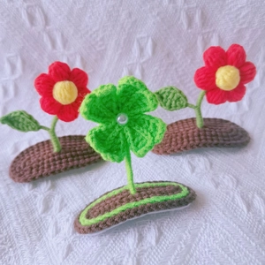 Detailed macro view of handmade crochet hair clips with red flower and green clover motifs