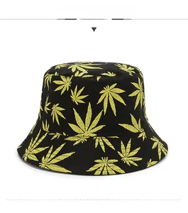 Close-up of black bucket hat featuring yellow maple leaf patterns and canvas texture