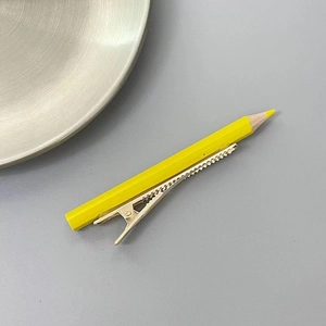 Détail de la pince à cheveux crayon jaune avec attache métallique argentée dentelée