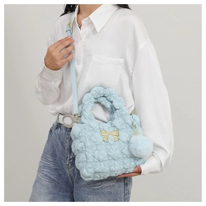 Detail of light blue quilted nylon bag with golden bow and soft pompom charm