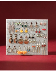 Detailed grid of assorted alloy and pearl earrings on gray velvet display organizer