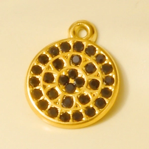 Macro shot of gold circular pendant featuring concentric rows of inlaid black rhinestones